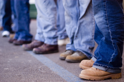 day-laborers group of people from the knees down wearing jeans and boots