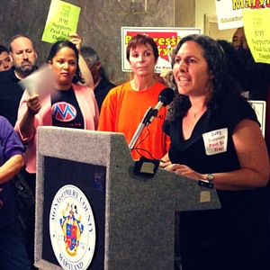 Rabbi Elizabeth Richman standing at a podium speaking while a group listens