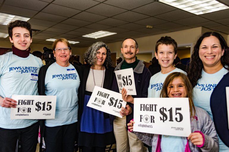 JUFJ leaders pose with signs that read "Fight for $15"