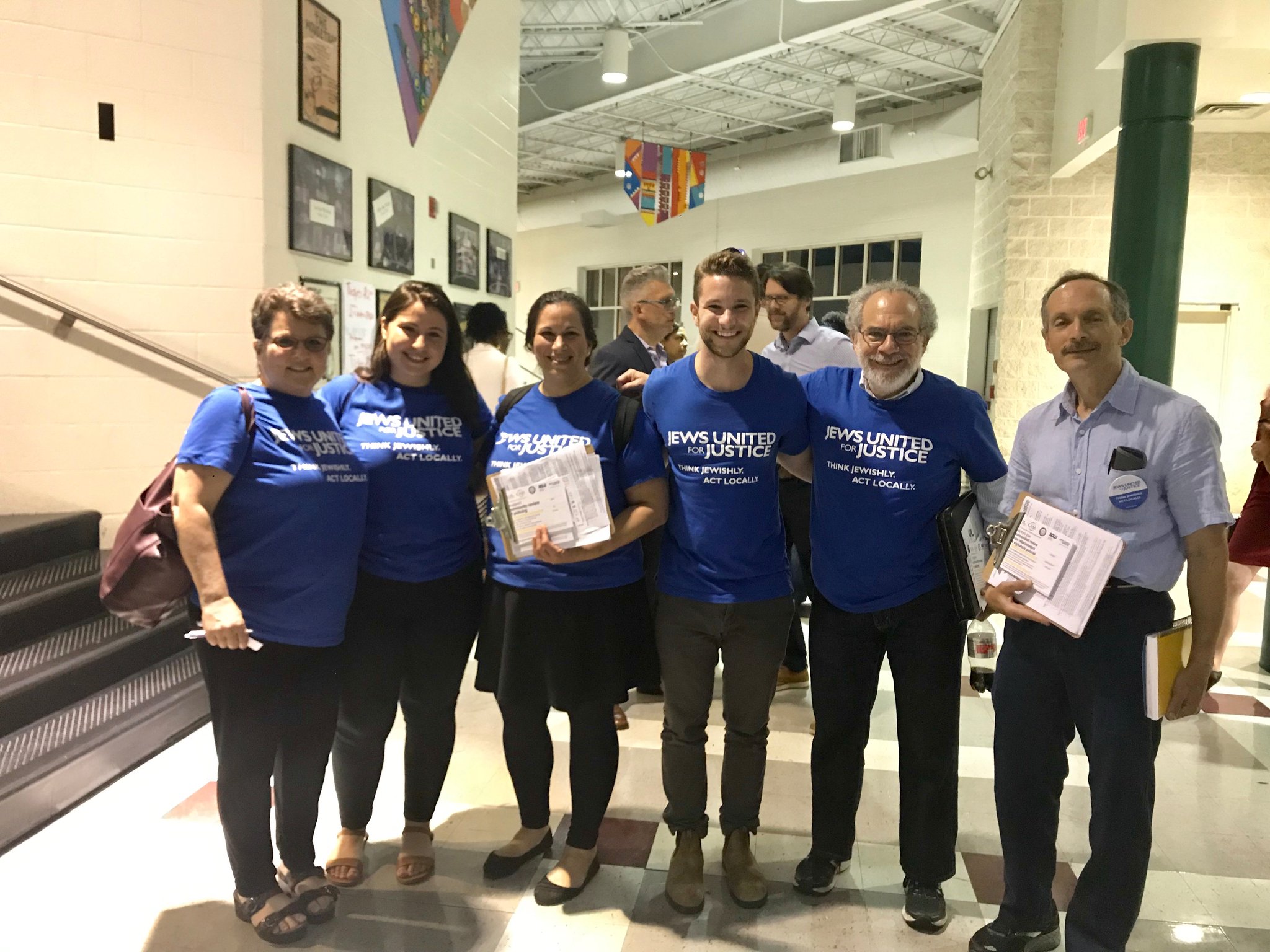 JUFJ members stand in a hallway wearing JUFJ shirts