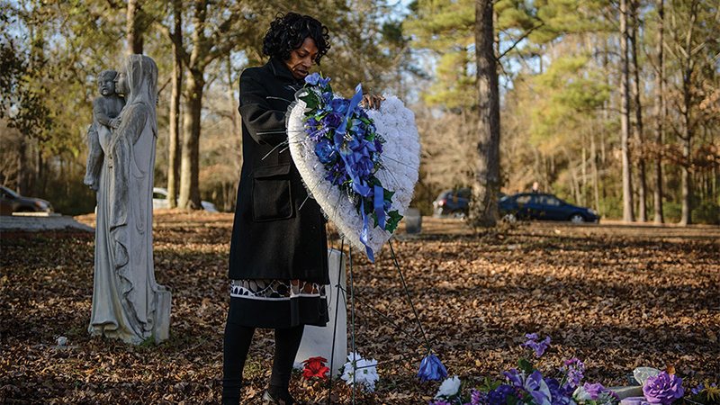 woman standing behind a memorial wreath