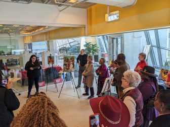 pxl_20230317_185032437 Molly Amster delivers remarks at University of Baltimore library beside paintings by Kimberly Sheridan